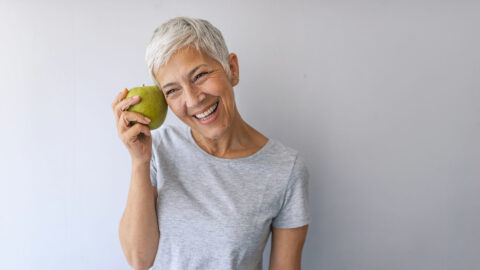 healthy middle aged woman smiling eating an apple